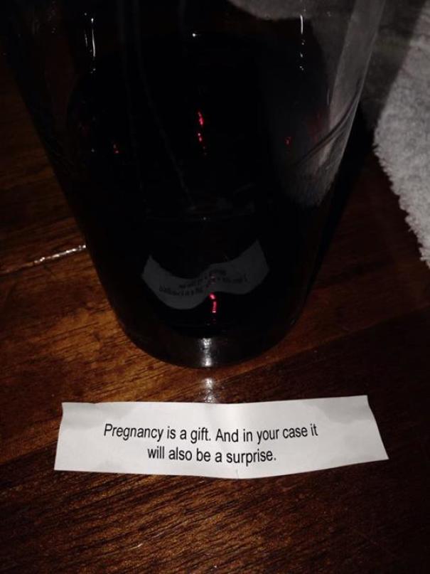 Sassy fortune cookie message on a table, with a glass in the background.