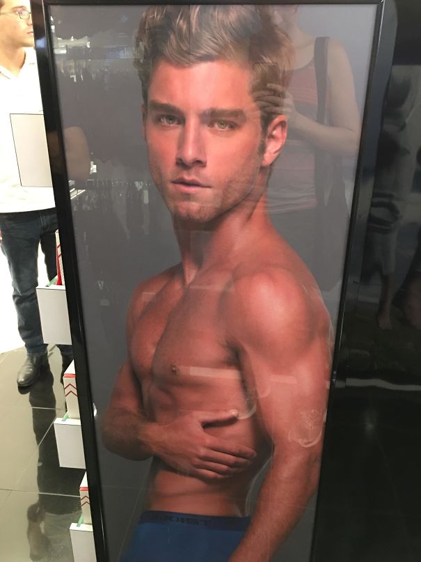 Poster of shirtless man with muscular body and distorted arm inside a glass frame, showcasing Photoshop fails.