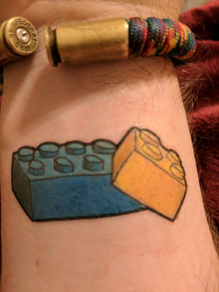 Tattoo of blue and yellow toy bricks on a person's skin, highlighting unique stories behind tattoos.