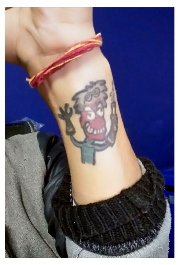 Colorful cartoon character tattoo on a forearm, showcasing a unique story behind the design.