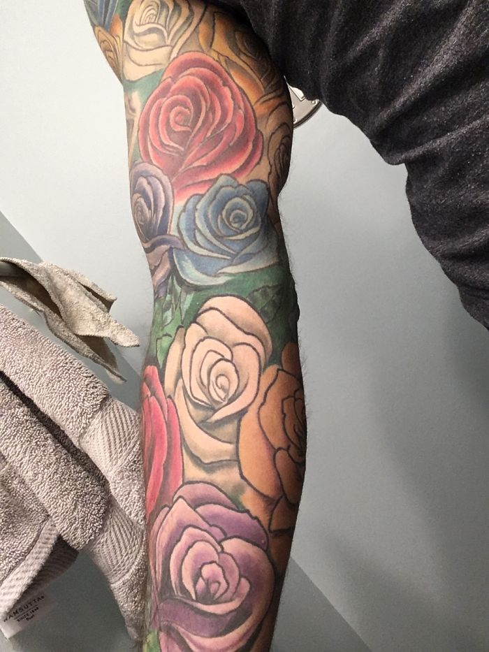 Colorful floral tattoos on a person's arm, showing vibrant roses and delicate details.