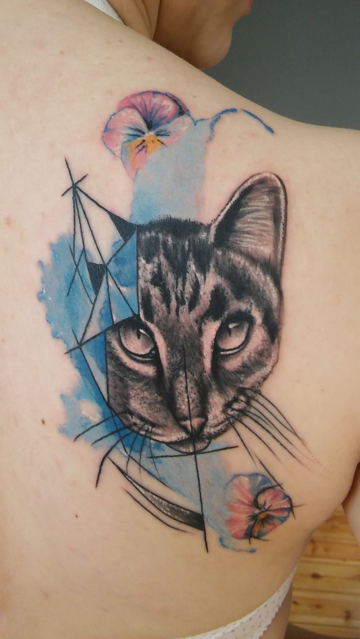 Cat tattoo design with colorful flowers and geometric shapes on the shoulder.