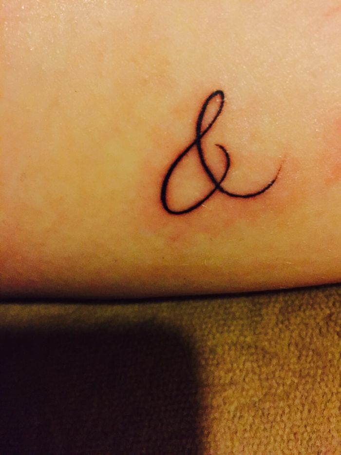 Close-up of ampersand tattoo on skin, showcasing personal tattoo stories.