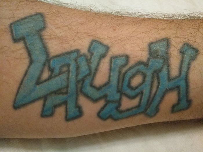 Blue graffiti-style "Laugh" tattoo on a forearm, showcasing personal tattoo stories.