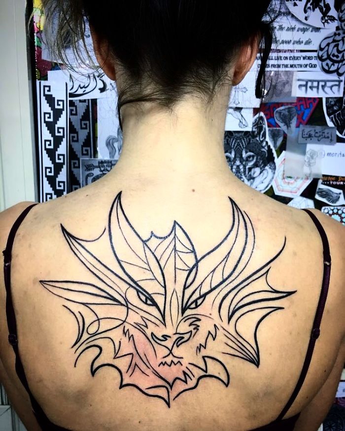 Back tattoo of a dragon outline, showcasing intricate design and personal stories behind tattoos.