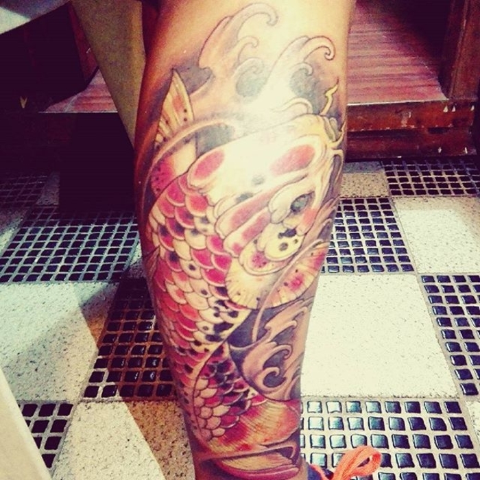 Colorful koi fish tattoo on a leg, showcasing intricate tattoo designs and artistic expression.