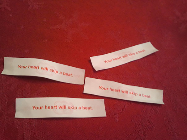 Four fortune cookie papers on a red surface, each reading "Your heart will skip a beat" in a sassy tone.