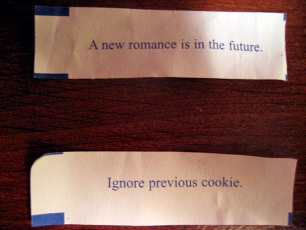Fortune cookie sayings: "A new romance is in the future" and "Ignore previous cookie" on a wooden table.