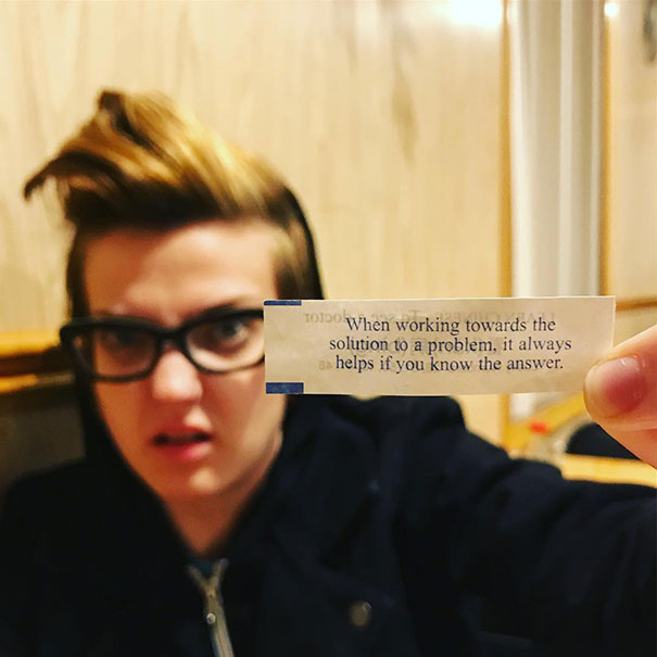 Person holding a sassy fortune cookie saying, reacting with a surprised expression.
