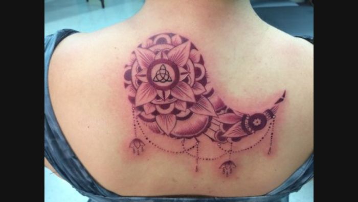 Mandala-style tattoo on a back, featuring floral patterns and a Triquetra symbol.