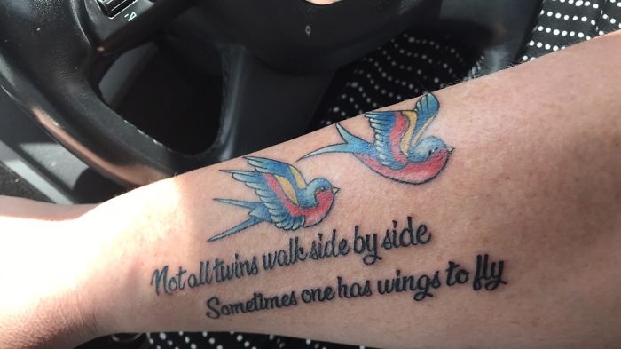 Tattoo of colorful birds with text about twins on forearm, sharing a personal story.