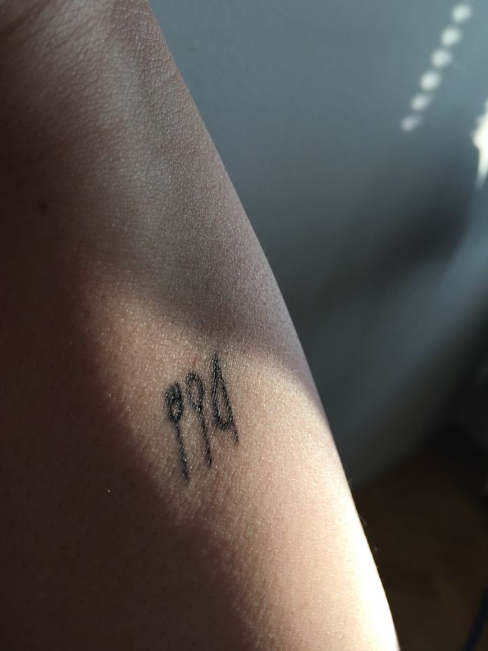 Minimalist tattoo on skin, depicting three small symbols, with sunlight casting shadows.