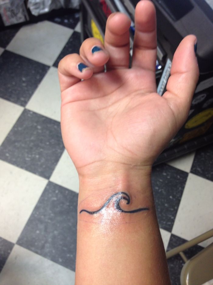 A wrist tattoo of a minimalist wave, symbolizing personal stories behind tattoos.