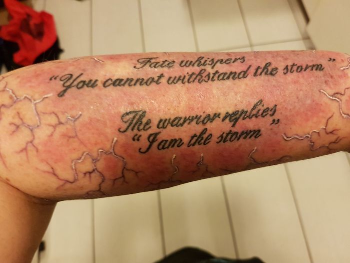 Forearm tattoo with a motivational quote about resilience and strength, featuring dark script on a light background.