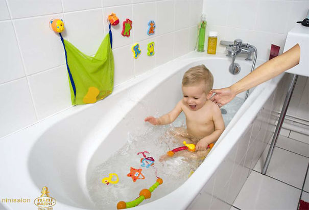 Toddler playing with bath toys in a white bathtub with adult hand reaching in, showcasing hilarious and disastrous Photoshop fails.