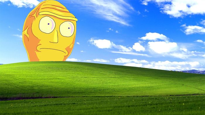 Genius desktop wallpaper featuring a humorous cartoon character on a grassy hill under a blue sky.