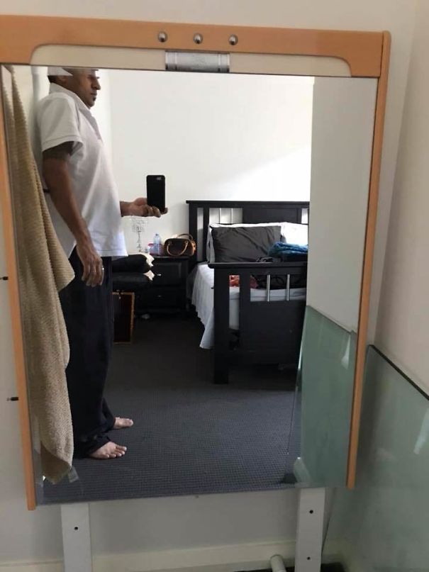 Person photographing a mirror for sale, capturing their reflection in a bedroom setting.