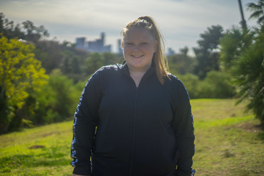 Young woman smiling outdoors in a park setting, participating in interviews on birthdays project.