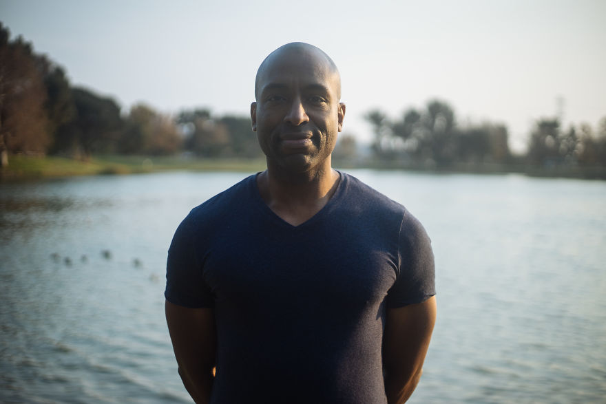 Man standing by a lake during golden hour, representing interviews with people on their birthdays in an outdoor setting.