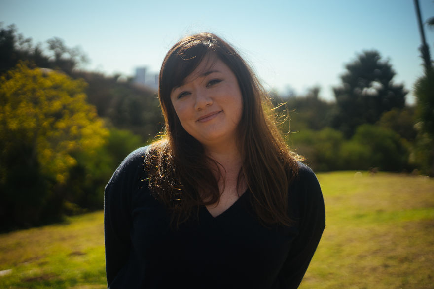 Woman smiling outdoors on a sunny day, featured in a project interviewing people on their birthdays.