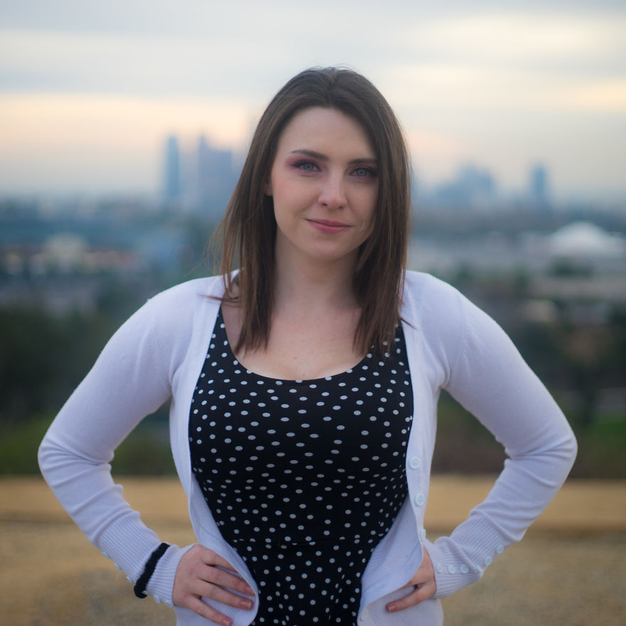 Woman standing outdoors with hands on hips, smiling confidently during a birthday interview session.