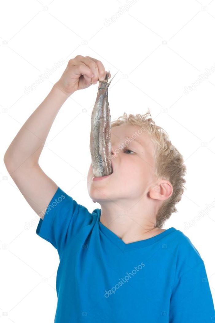 Little boy in blue shirt eating a herring