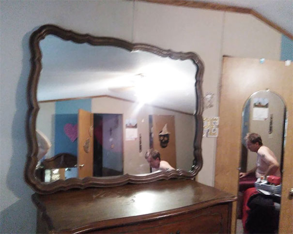 Man captured in a room reflection while attempting to sell a mirror online.