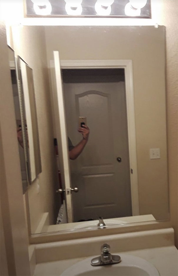 Person taking photo of a mirror set, capturing their own reflection awkwardly with a smartphone camera.