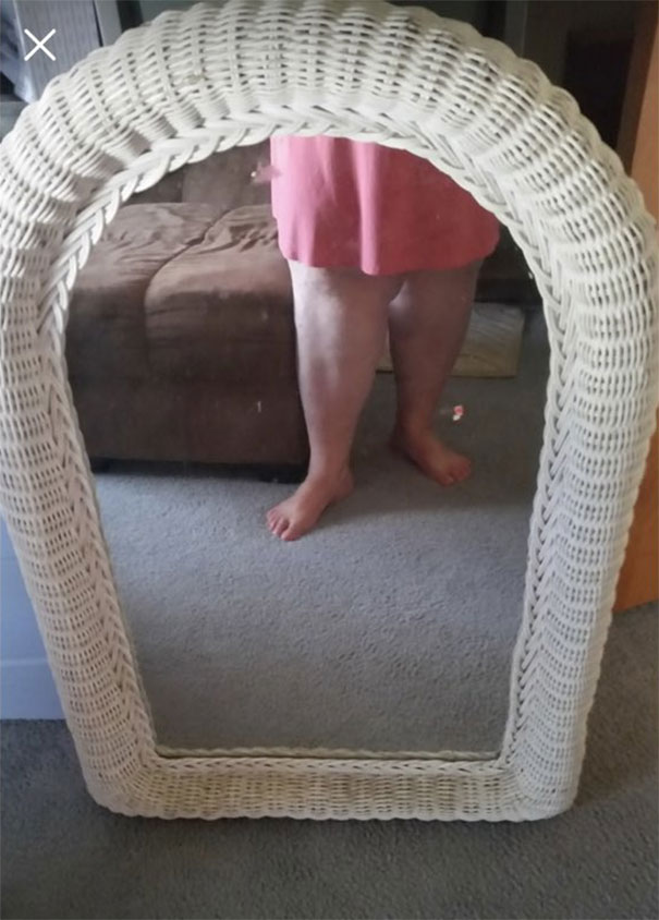 Person taking a mirror selfie, showing legs and a wicker mirror, highlighting funny attempts to sell mirrors.