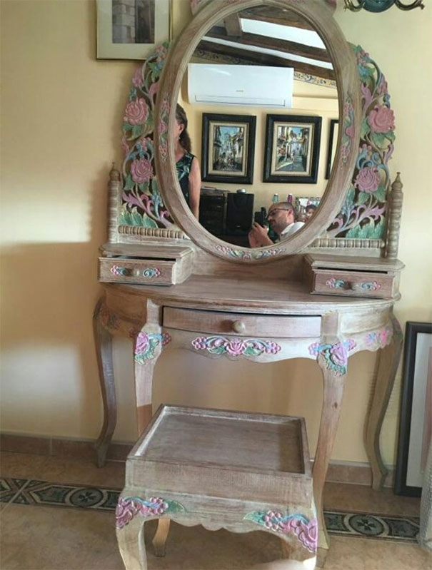 A mirrored vanity with floral carvings, reflecting people in a cozy room, highlighting the charm of selling mirrors.