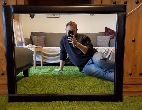 Person posing in front of a mirror for sale, capturing their reflection in a cozy living room setting.