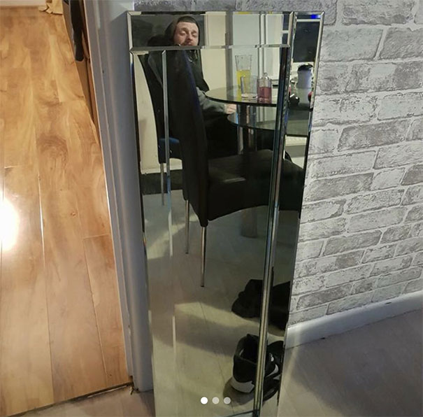 Person reflected in a mirror for sale, seated at a table, capturing curiosity in unique perspectives on selling mirrors.