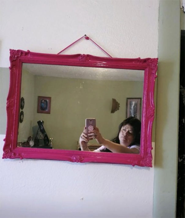Person taking a selfie in a pink-framed mirror, illustrating mirror-selling attempts.