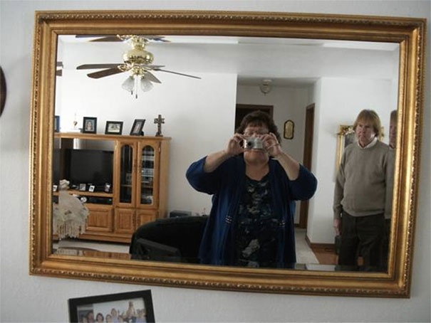 Person taking a photo of themselves in a mirror for sale, reflecting a room interior.