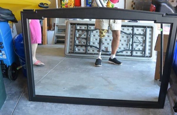 Person reflected in a mirror for sale, showing one leg with a prosthetic, pink shorts visible on left side.