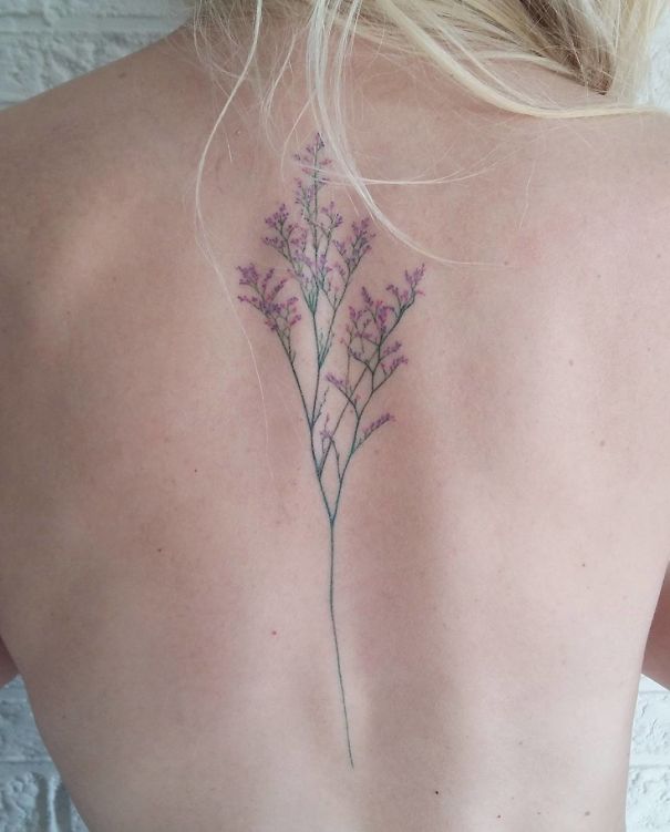 Delicate floral spine tattoo design on a person's back.