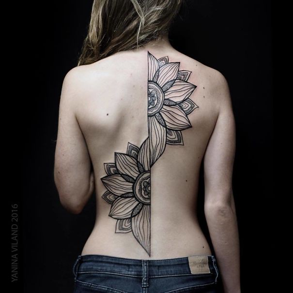 Detailed floral spine tattoo design on woman's back.
