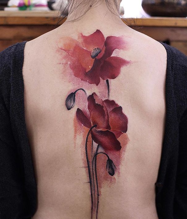Watercolor flower spine tattoo design on a woman's back.