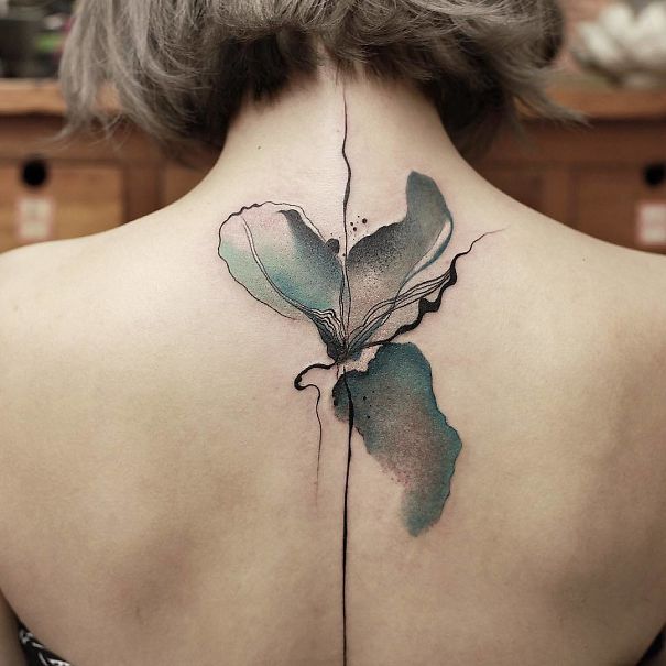 Abstract floral spine tattoo design in watercolor style on a person's back.