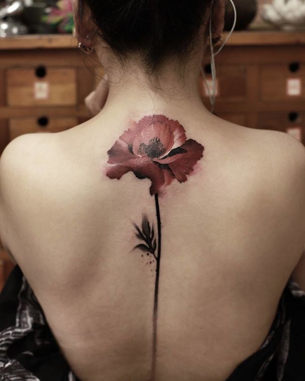 Red flower spine tattoo on a woman's back, showcasing a unique and elegant design idea.