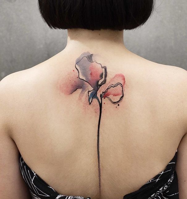 Watercolor flower spine tattoo on a woman's back.