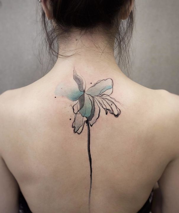 Watercolor flower spine tattoo with delicate blue and black ink design.