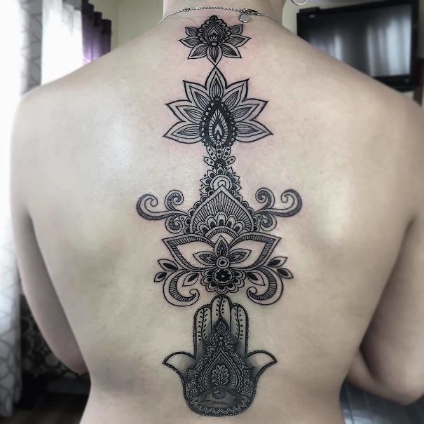 Intricate spine tattoo with floral and geometric designs in black ink.
