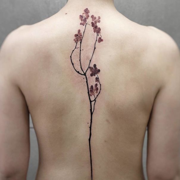 Delicate floral spine tattoo design on a person's back.