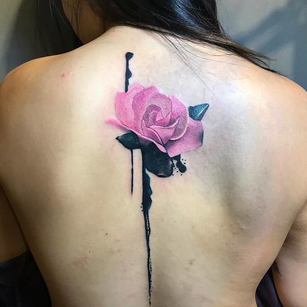 Pink rose spine tattoo with black ink accents on back.