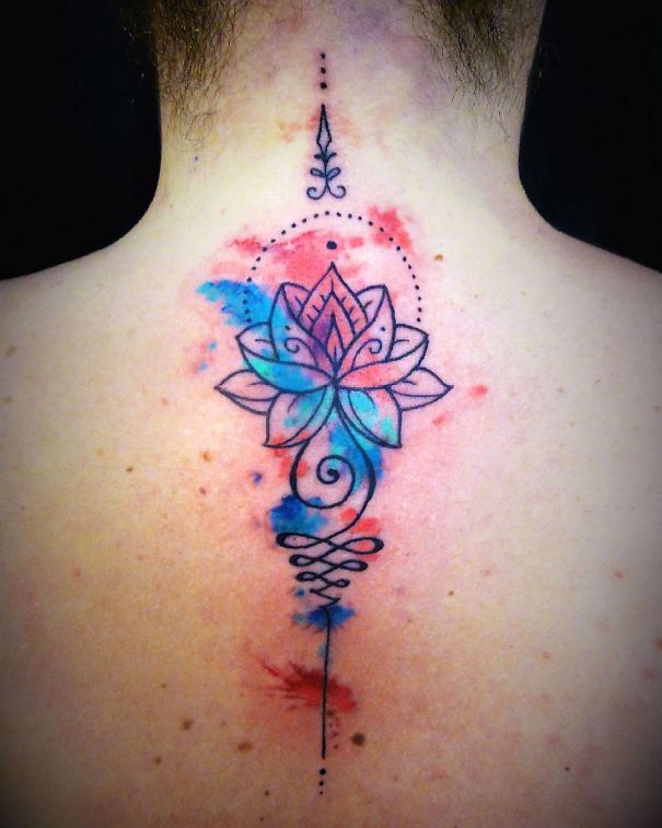 Colorful lotus spine tattoo design with watercolor accents.
