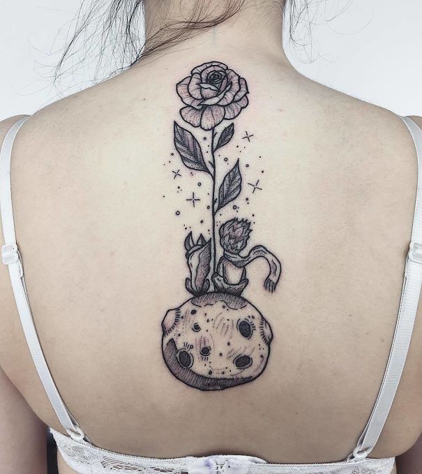 Rose and planet spine tattoo design on woman's back, wearing a white bra.