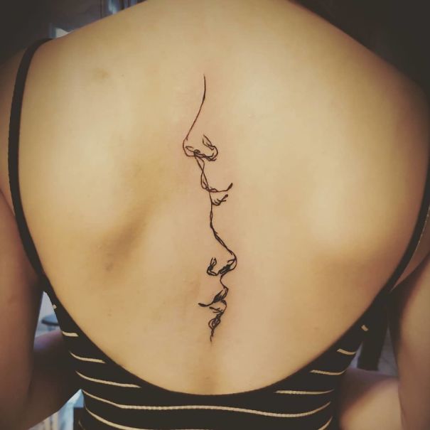 Delicate line art spine tattoo on a woman's back.