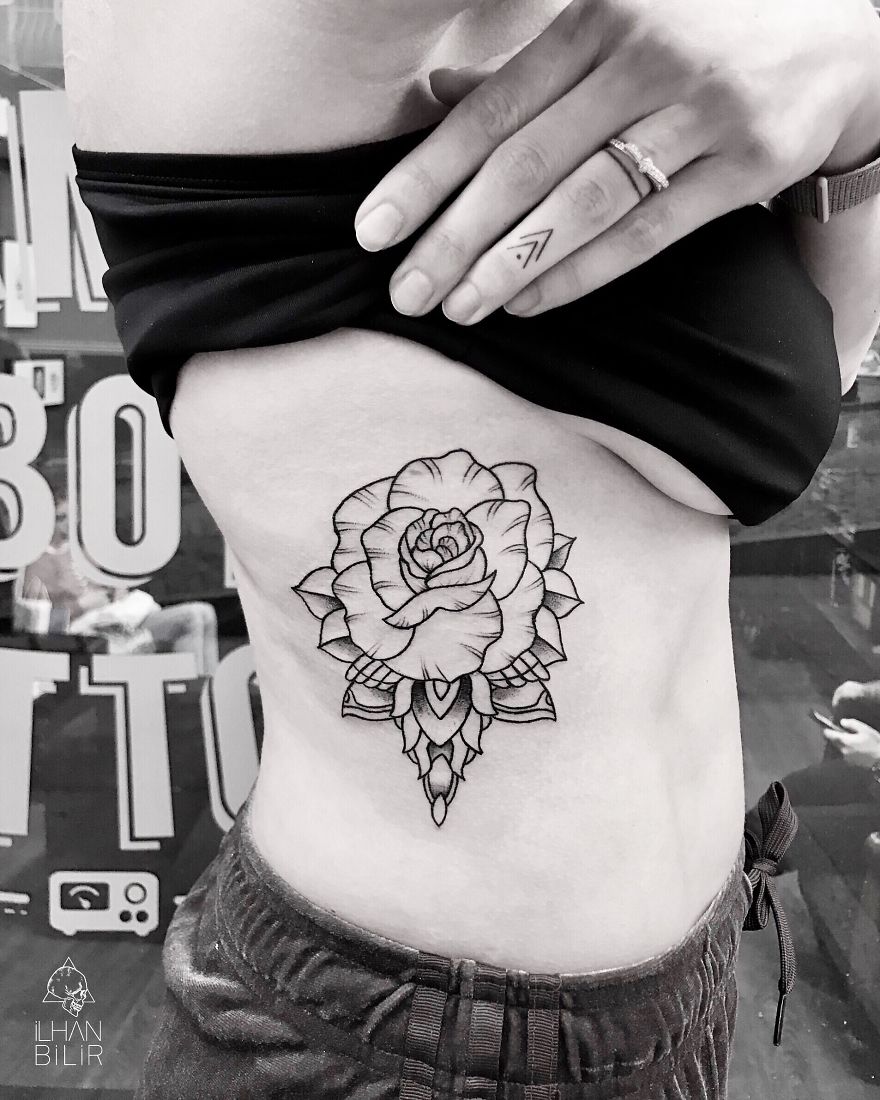 Tattoo of a rose with dotwork design on a person's side by artist Ilhan Bilir, showcasing simplicity and contrast.
