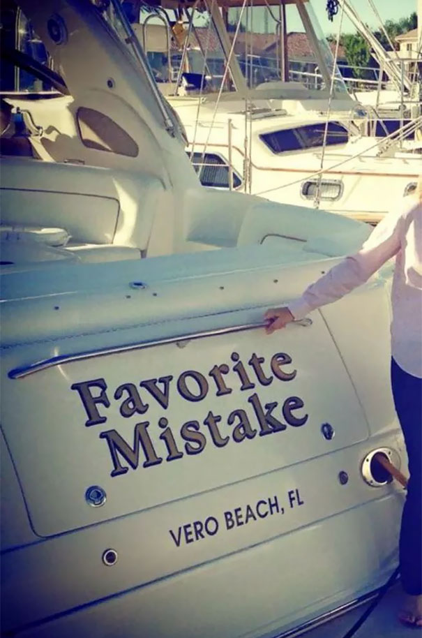 Woman posing next to a funny named white boat 